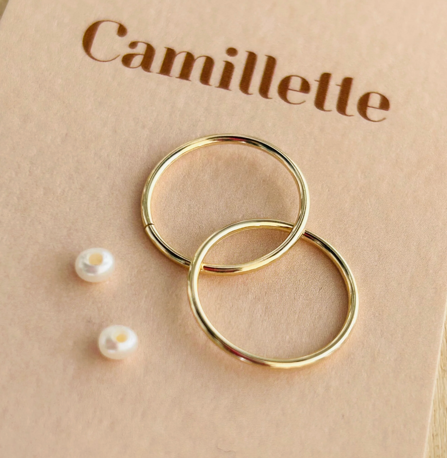 A shiny pair of sleepers with pearl on a camillette background