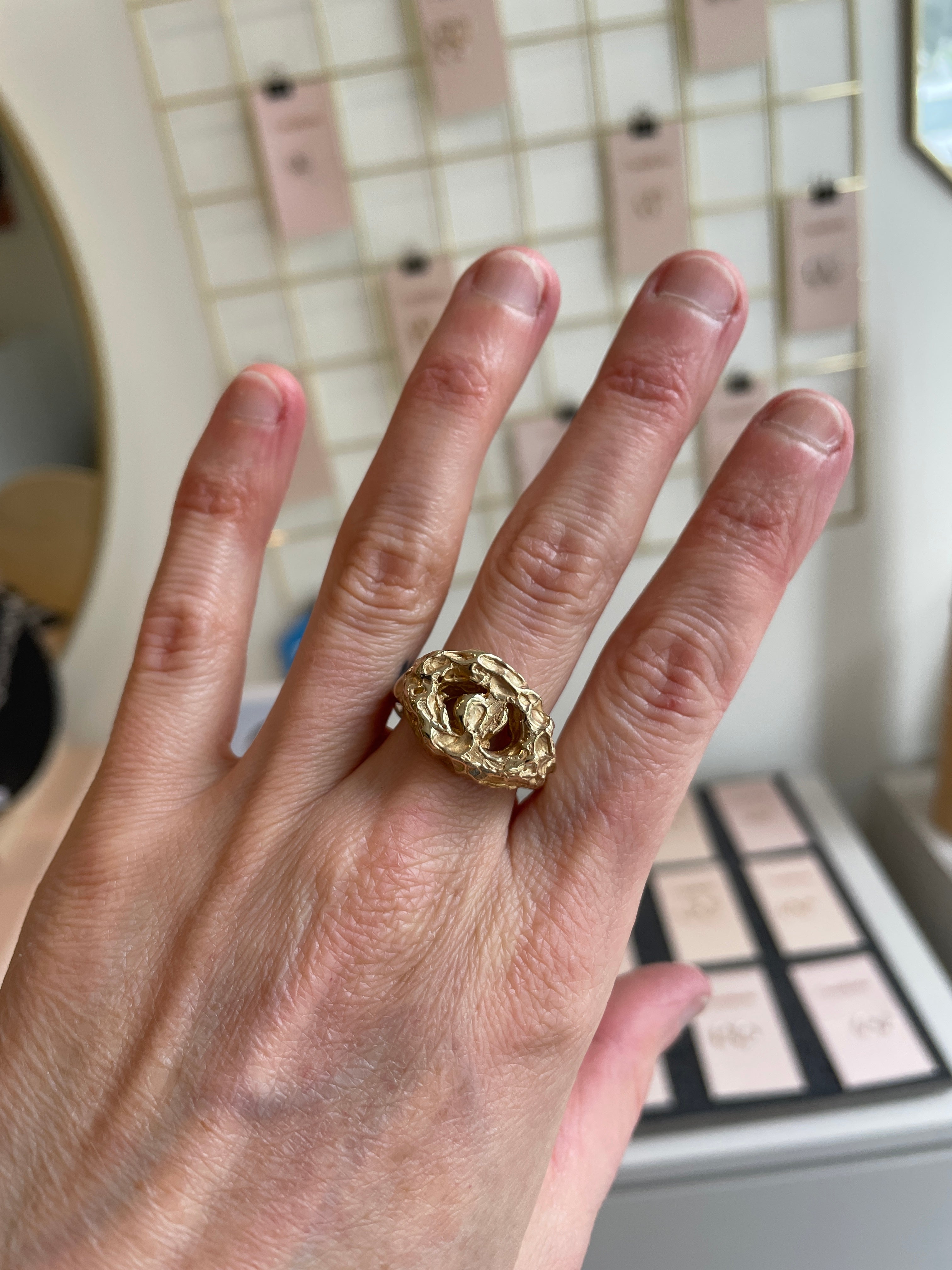 Hand wearing a gold ring with a blurred background