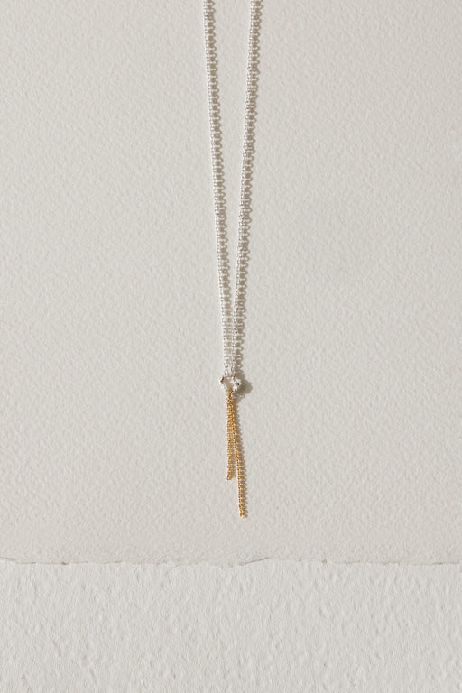 Silver necklace with a 10k gold chain dangling from a textured circle charm by Camillette Jewelry