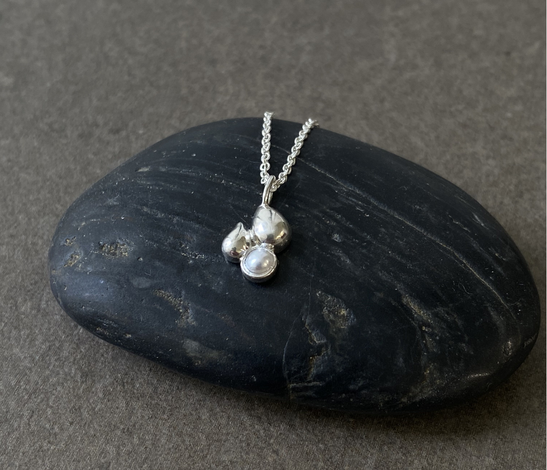 Silver necklace with a pendant on a dark stone surface