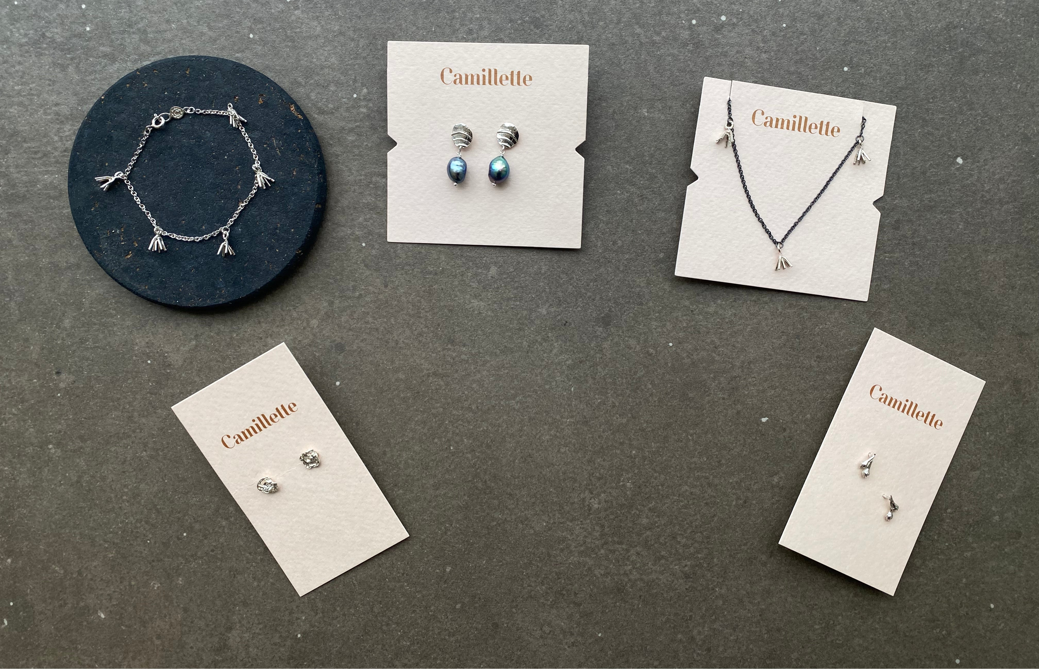 Collection of Camilllette jewelry including a bracelet, necklace, and earrings on gray surface.