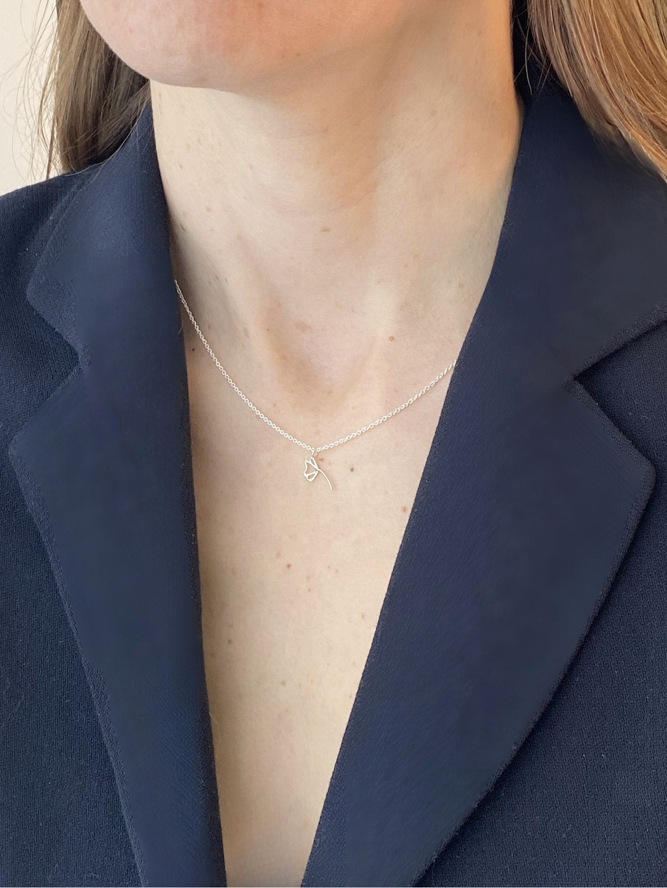 Person wearing a delicate necklace with a plain background