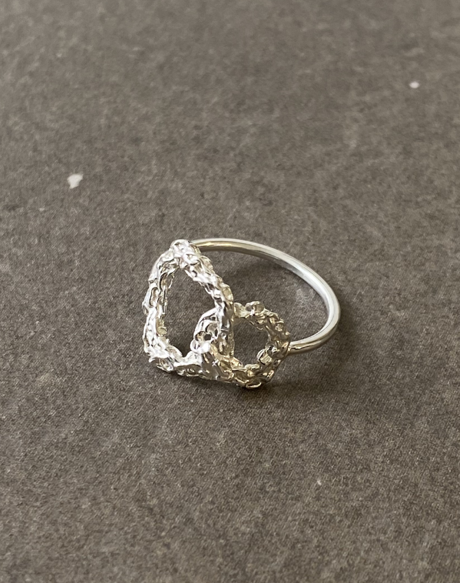 Silver ring with a textured design on a gray surface